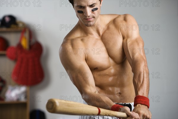 Baseball player with bare chest warming up with bat. Date : 2008