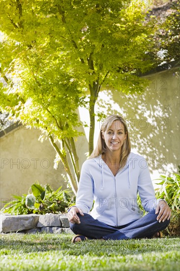 Portrait of woman sitting cross-legged in yard. Date: 2008