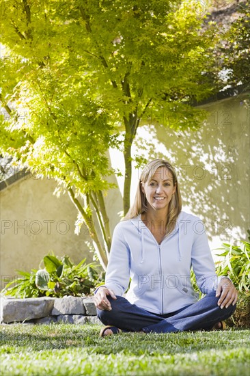 Portrait of woman sitting cross-legged in yard. Date : 2008