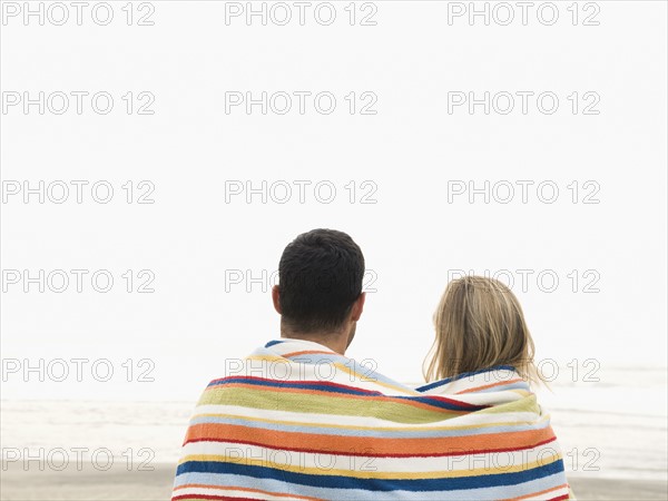 Couple wrapped in towel on beach. Date: 2008