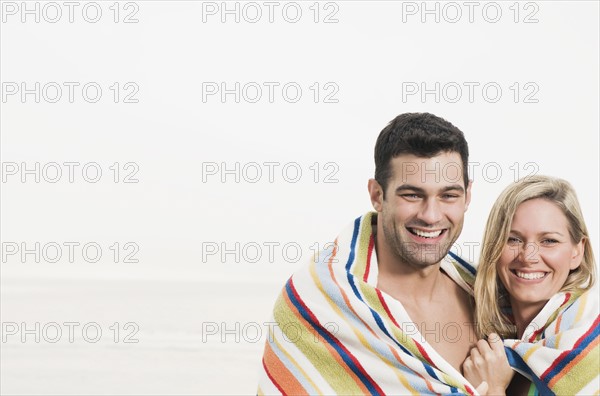 Portrait of couple wrapped in towel at beach. Date : 2008