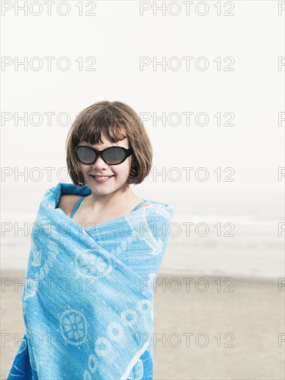 Portrait of girl in sunglasses wrapped in a towel on beach. Date : 2008