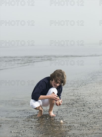 Girl finding seashells on beach. Date: 2008