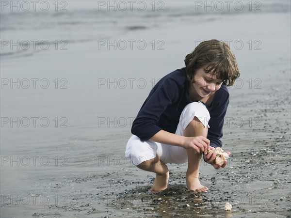Girl finding seashells on beach. Date : 2008
