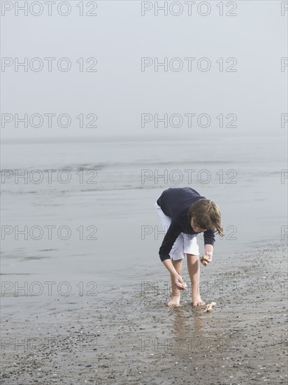 Girl finding seashells on beach. Date: 2008