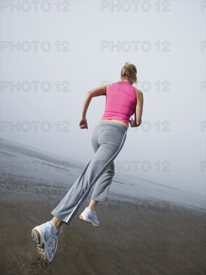 Woman jogging on foggy beach. Date : 2008