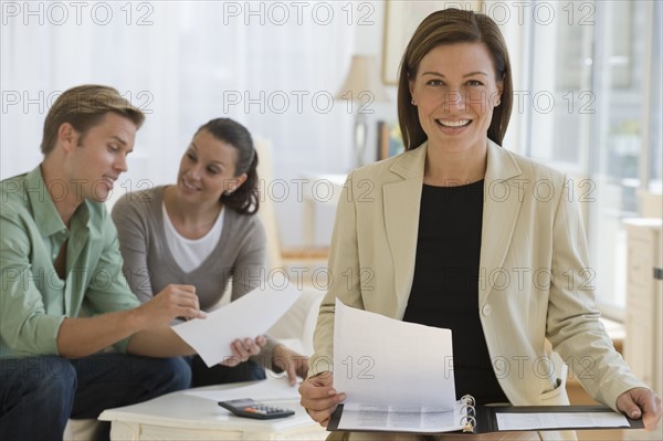 Female financial advisor with couple in background.