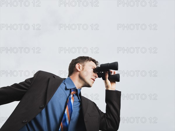 Businessman looking through binoculars. Date : 2008