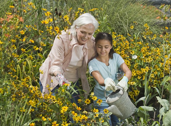 Grandmother and granddaughter watering plants.