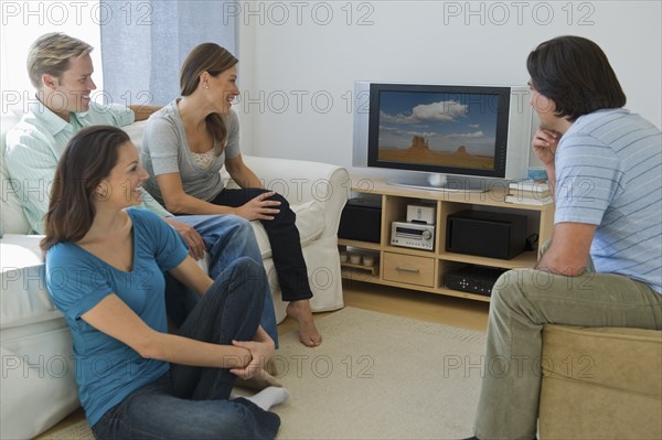 Couples watching television in living room.