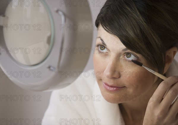 Woman applying makeup vanity mirror.