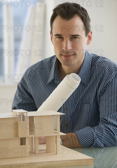 Portrait of architect with blueprints and building model.