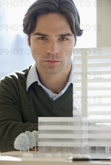 Architect posing with building model.