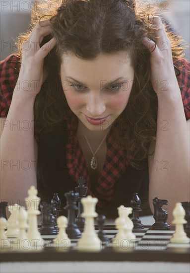 Close up of woman looking down at chessboard.