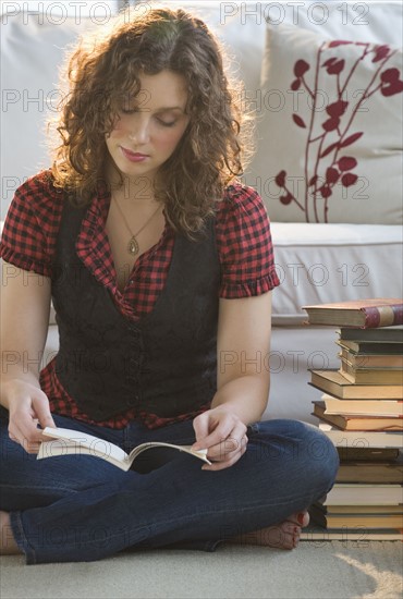 Woman reading book on living room floor.