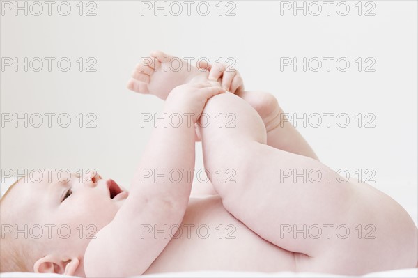 Naked baby laying on back and grabbing feet. Date: 2008