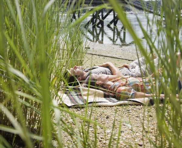 Couple laying on blanket near lake. Date: 2008