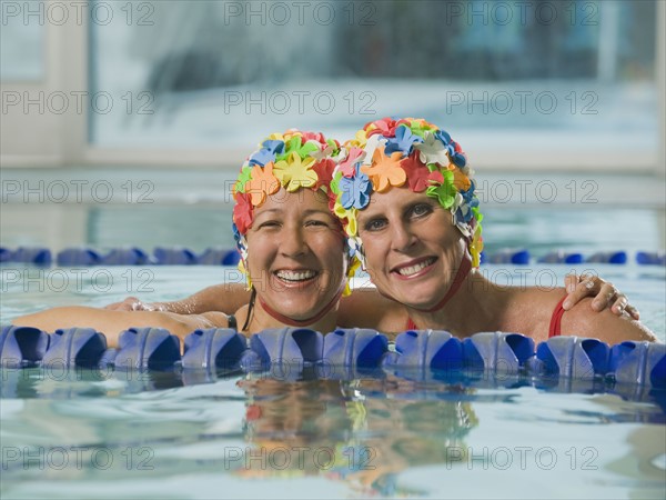 Women in swim caps hugging in swimming pool. Date : 2008