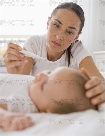 Worried mother checking baby son’s temperature.