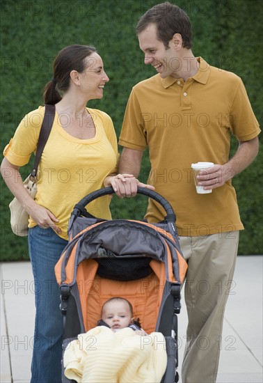 Happy couple walking baby in stroller.