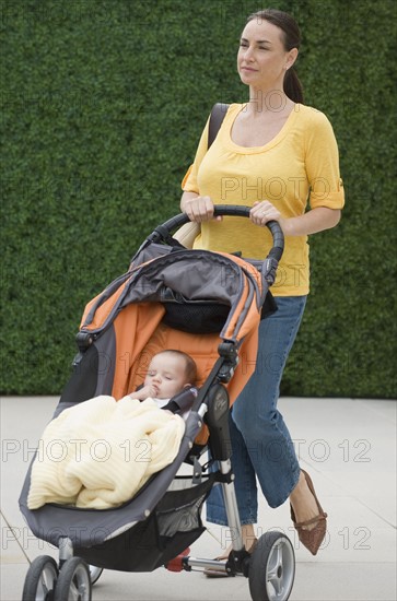 Mother walking baby son in stroller.