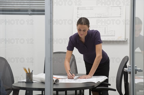 Architect working on blueprints in office.