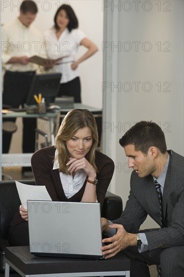 Businessman and businesswoman using laptop.