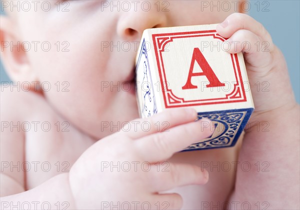 Close up of baby biting on alphabet block. Date : 2008