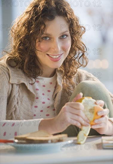 Portrait of woman peeling orange.