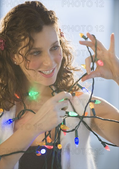 Woman untangling Christmas string lights.