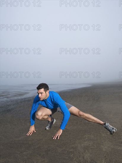 Man stretching on foggy beach. Date: 2008