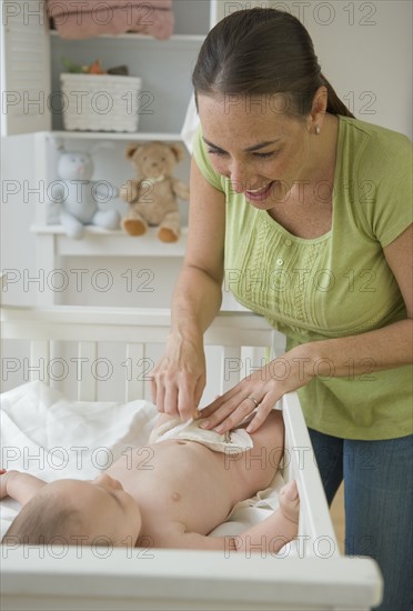 Mother changing baby son’s diaper.