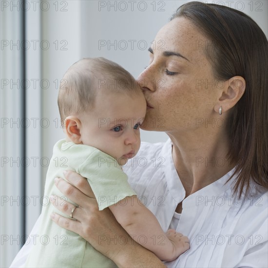 Mother kissing baby son.