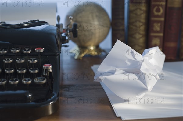 Crumpled paper next to antique typewriter.