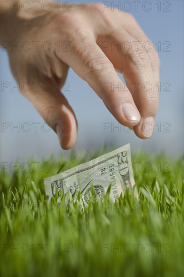 Close up of hand reaching for twenty dollar bill.