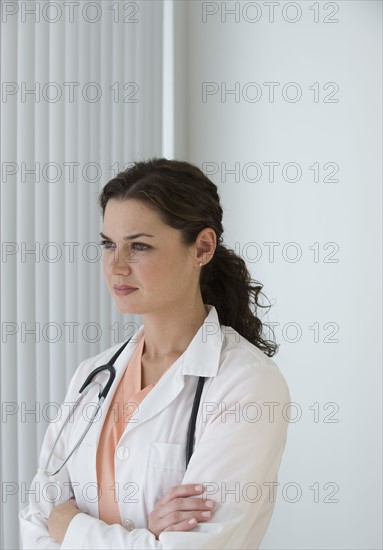Female doctor looking out window pensively.