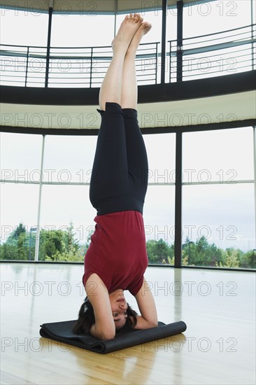 Woman in headstand yoga pose. Date : 2008