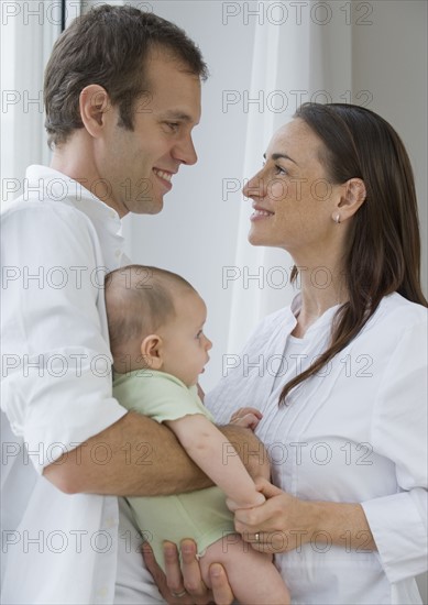 Couple standing face to face holding baby son.