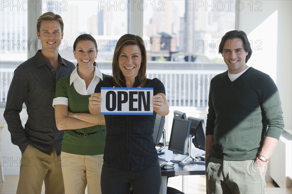 Portrait of business people holding ”Open” sign.
