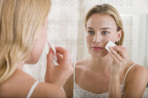 Woman applying makeup in bathroom.