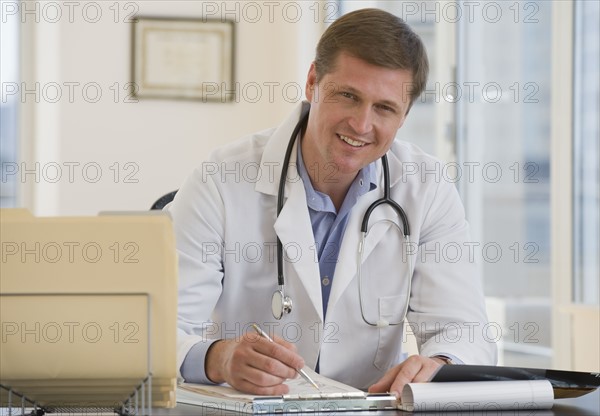 Male doctor posing at desk.