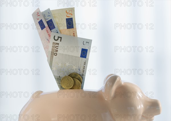 Close up of euros sticking out piggybank.