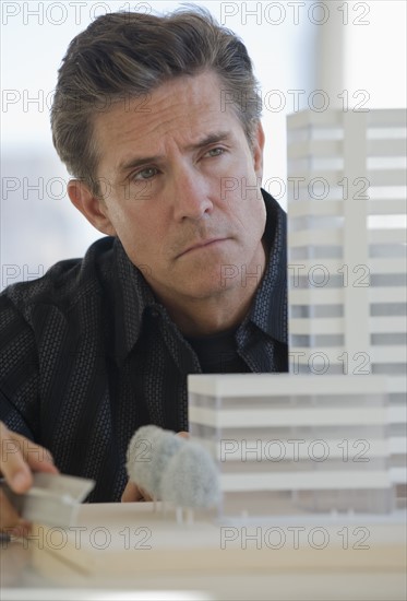 Close up of architect examining building model.