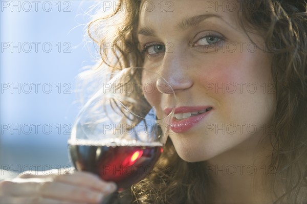 Close up portrait of woman smelling red wine.