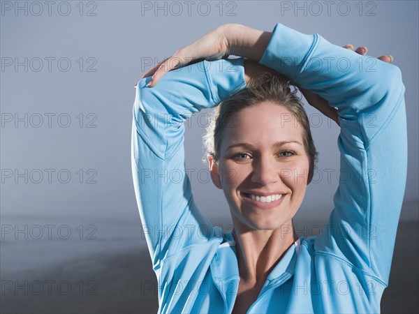 Close up of woman with hands overhead on foggy beach. Date : 2008