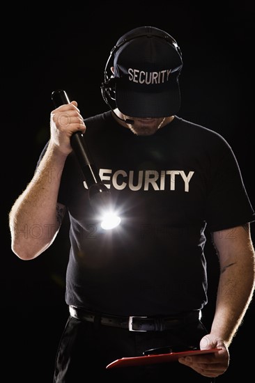 Bouncer looking at guest list with flashlight. Date : 2008