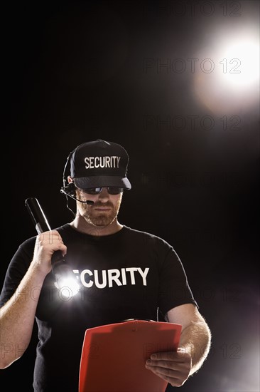 Bouncer looking at guest list with flashlight. Date : 2008