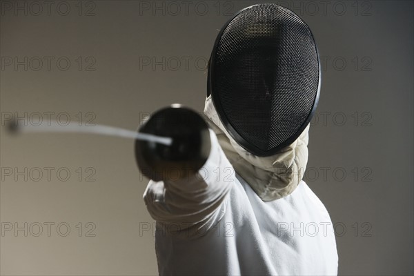 Close up of fencer in mask pointing fencing foil