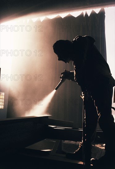 Factory worker sandblasting industrial equipment. Date : 2008