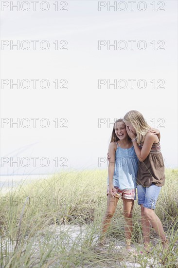 Girls whispering in beach grass. Date : 2008